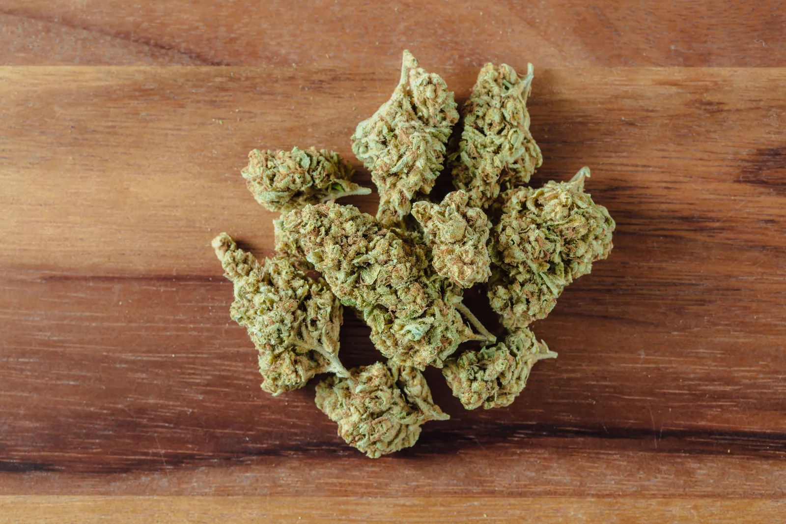 Close-up of dried cannabis buds neatly arranged on a rustic wooden surface. The well-cured flowers reflect premium craftsmanship, similar to the high-grade products offered by the Top 10 Dispensaries in Minnesota.