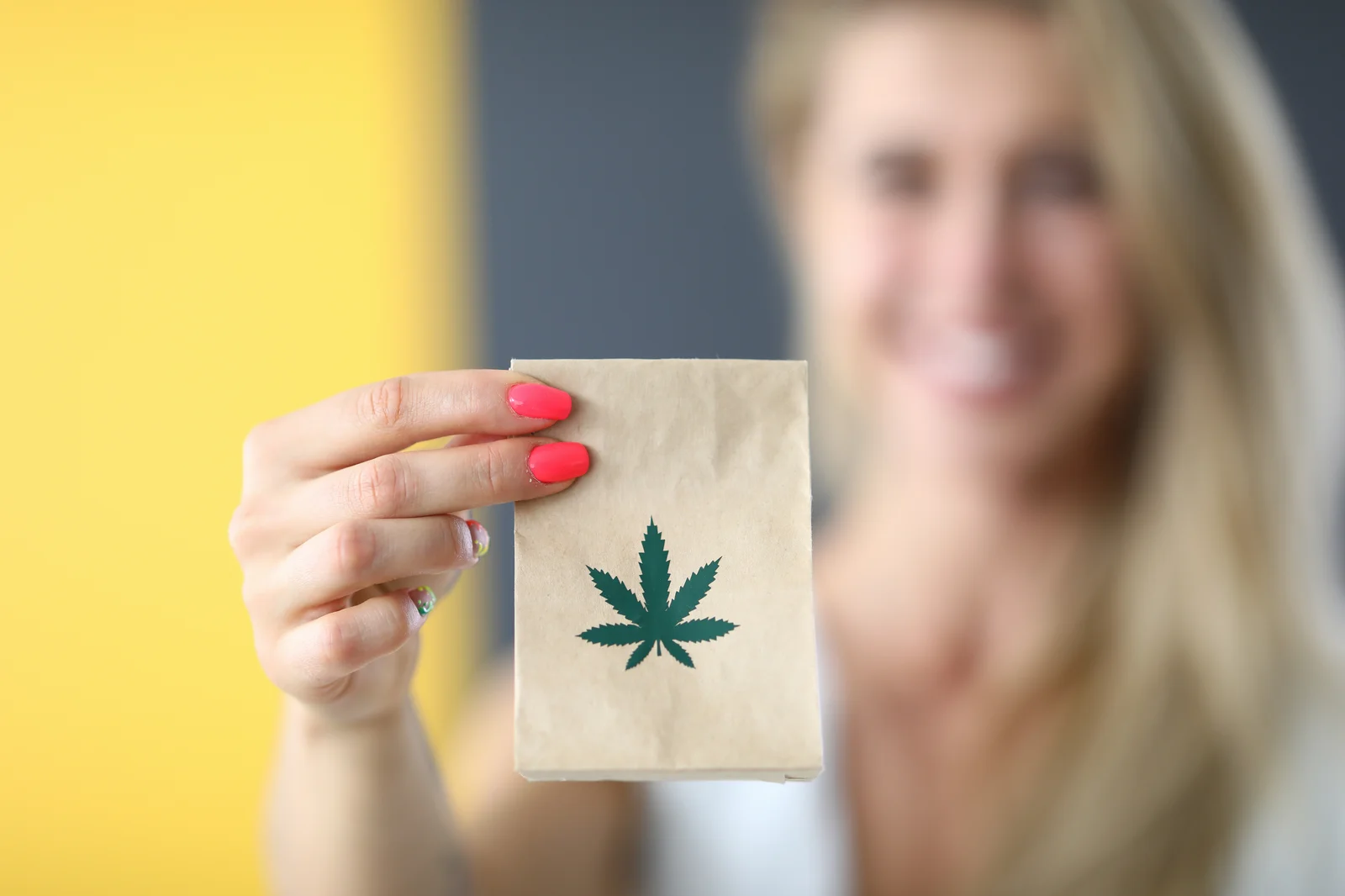 Smiling woman holding a cannabis-branded package, highlighting packaging solutions and retail consulting by New Jersey Cannabis Consultants.