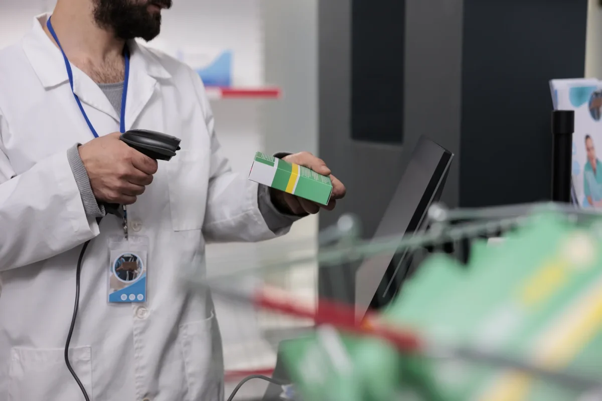 A pharmacist scans a product box in a pharmacy, representing the precision needed in tracking plant-based products and raising questions like “How Long Does It Take a Cannabis Plant to Grow?” in regulated markets.