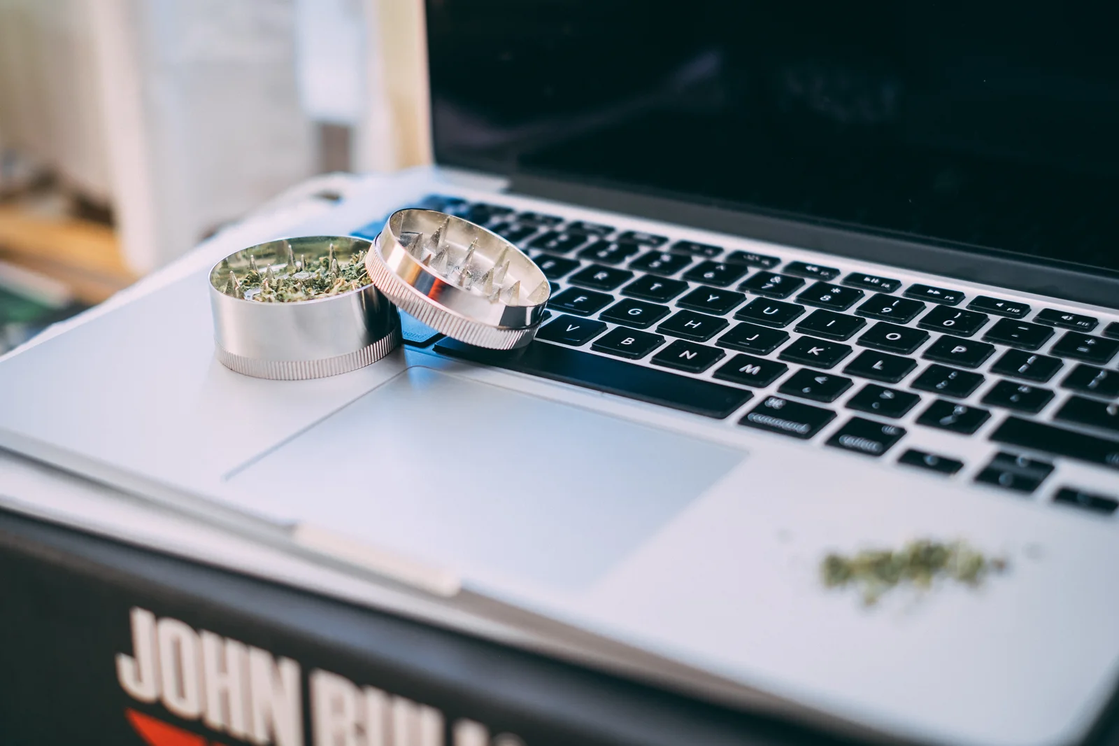 A cannabis grinder and laptop on a desk illustrating what is seed-to-sale software through its role in digital inventory control and product traceability.