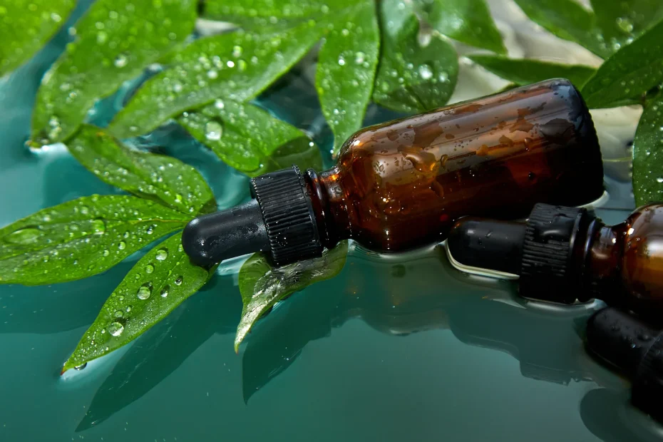 Amber dropper bottles on fresh wet leaves, representing natural wellness products like cannabis tinctures.