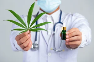 Medical professional holding a cannabis leaf and a tincture bottle, showcasing Hemp-Derived CBD in healthcare context.