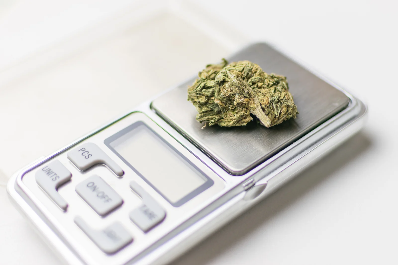 A single cannabis bud placed on a portable digital scale, representing compact and reliable scales for cannabis for precise weighing.