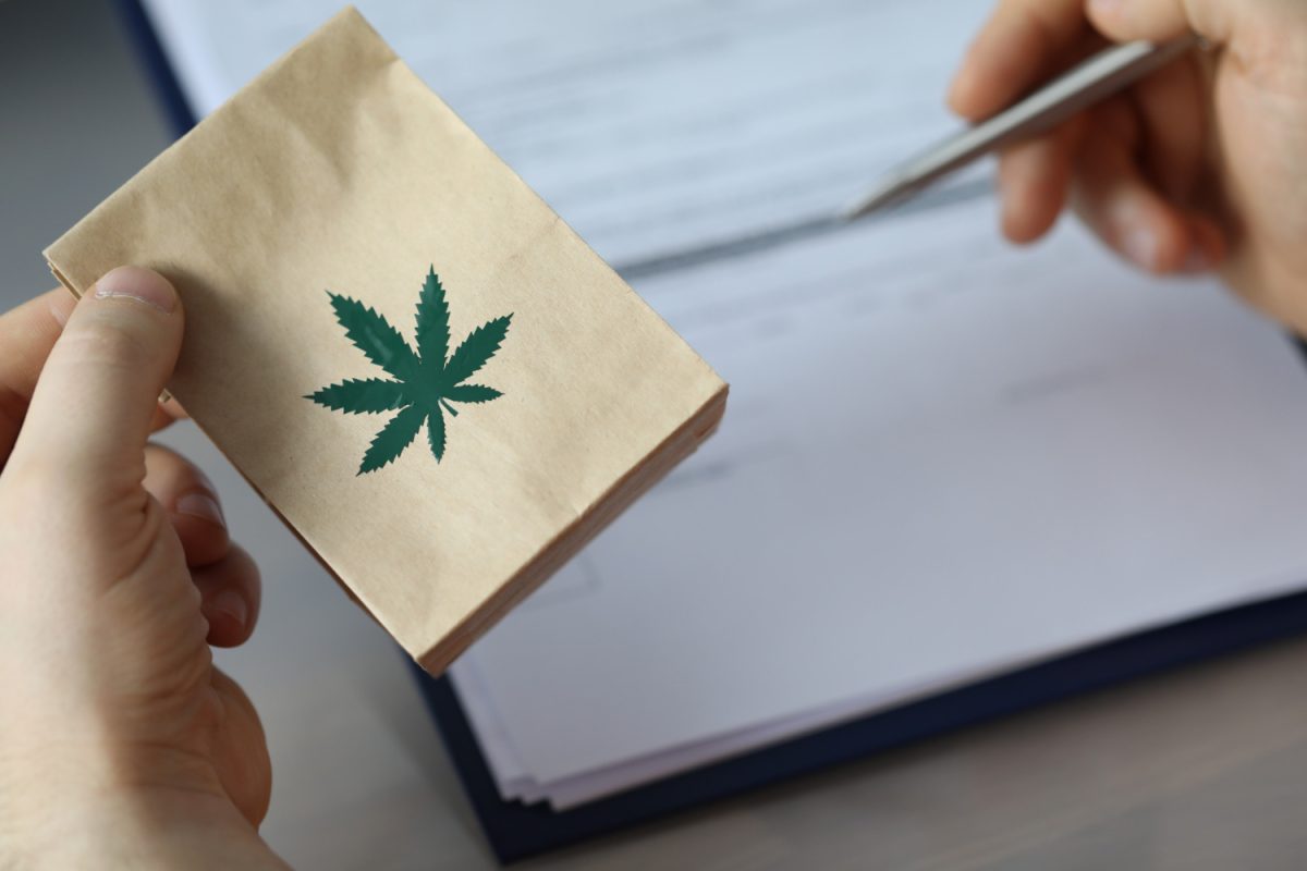 Hands holding cannabis-branded paper packet