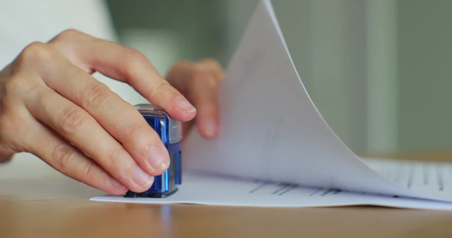 A close-up of hands stamping documents, illustrating the application and approval process for a cannabis license Florida.